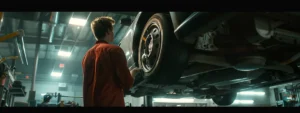 a mechanic inspecting a shiny, well-maintained brake rotor on a lifted car in a clean workshop.